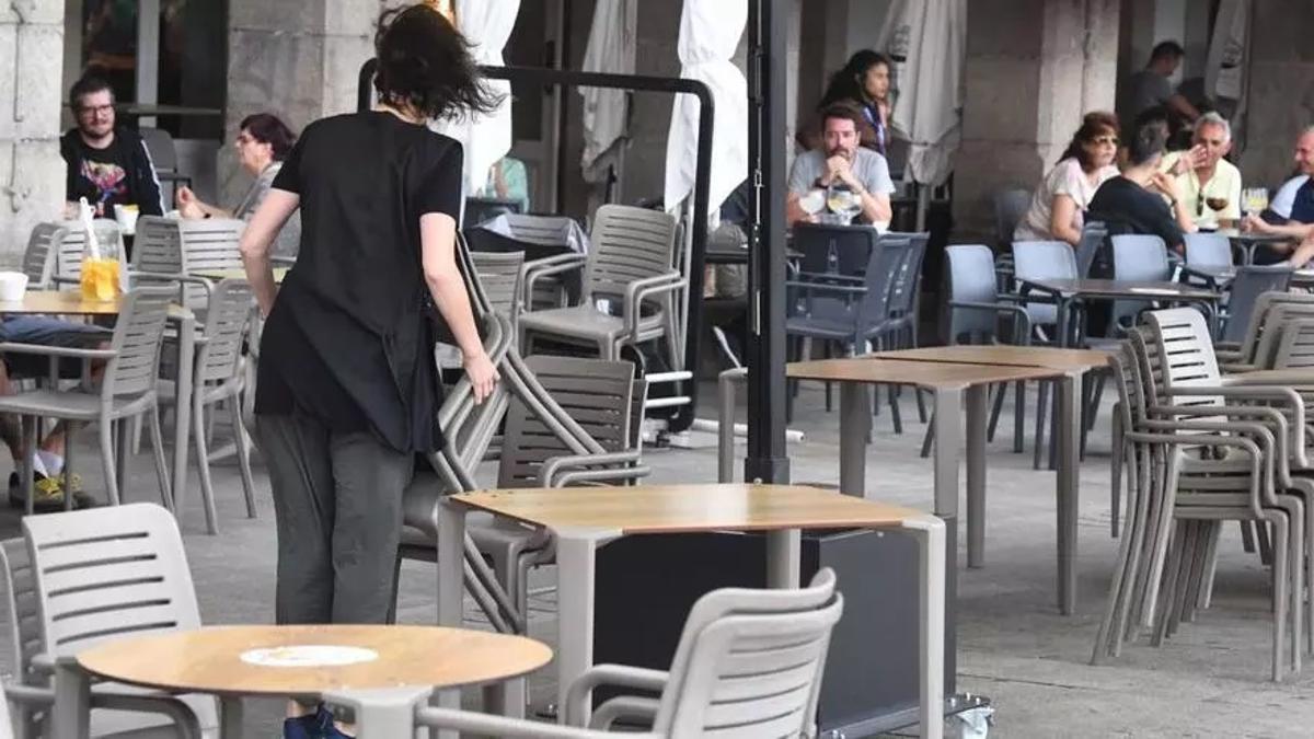 Una hostelera recogiendo las sillas de una terraza.
