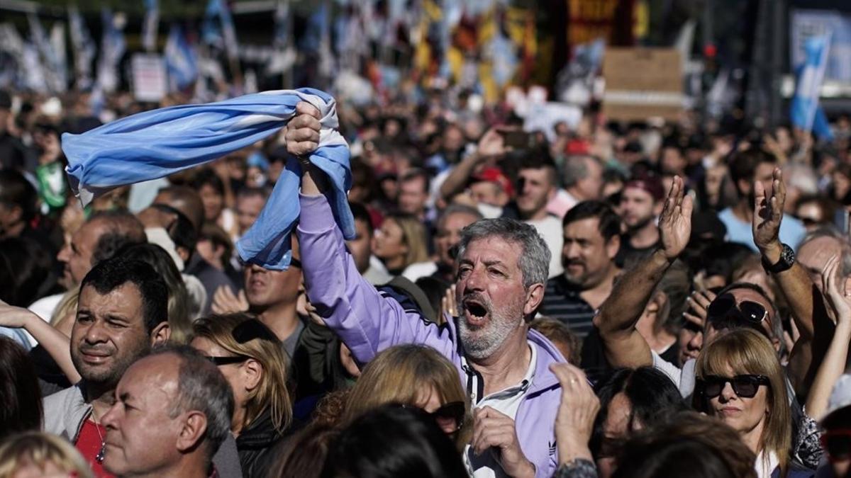 Un hombre empuña la bandera argentina entre la multitud que ha tomado las calles de Buenos Aires para protestar por la situación económica del país.