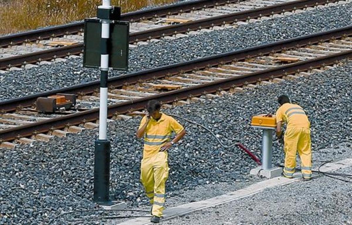 Operaris d’Adif revisen el lloc de l’accident (a dalt) i repassen les balises al costat de la via (a baix), ahir.