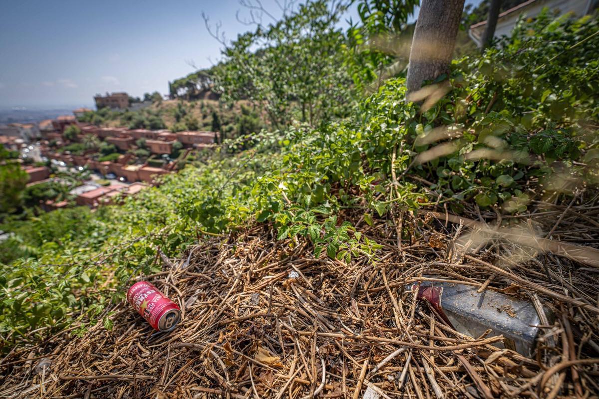 Zona de la carretera de les Aigües donde, según denuncian los vecinos, se celebran botellones durante la noche. En la imagen, una botella de vidrio abandonada junto a numerosas colillas en un área donde, aseguran, algunas personas también acampan y dejan residuos que incrementan el riesgo de incendio en el parque natural de Collserola. Barcelona, 14 de julio de 2026. AUTOR: Manu Mitru | EPC