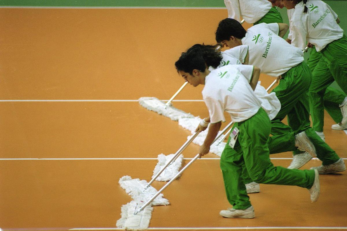 Voluntarios olímpicos limpiando la pista durante un partido de voley en los Juegos Olímpicos de Barcelona