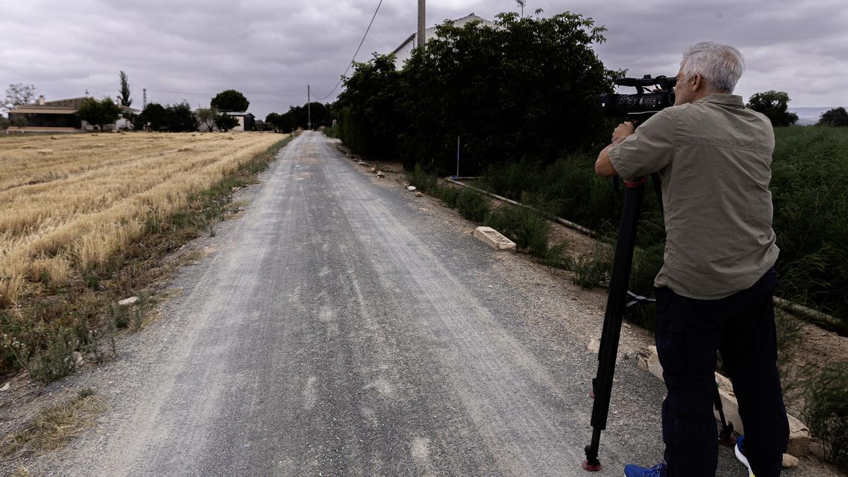 Un reportero graba imágenes del camino que lleva a la vivienda de la mujer de 50 años que ha sido hallada muerta en una cuneta de la localidad malagueña de Antequera.