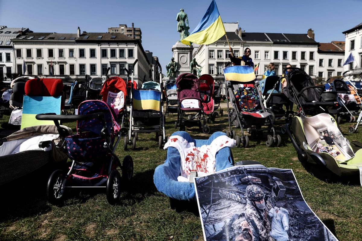 Cerca del Parlamento Europeo (UE) en Bruselas, muestra cochecitos vacíos, imágenes de jóvenes víctimas de la guerra en Ucrania y ropa de bebé cubierta con sangre falsa, durante una protesta para apoyar y resaltar la difícil situación de los niños víctimas de la guerra, en el segundo día de la cumbre de la UE para discutir la invasión de Rusia a Ucrania