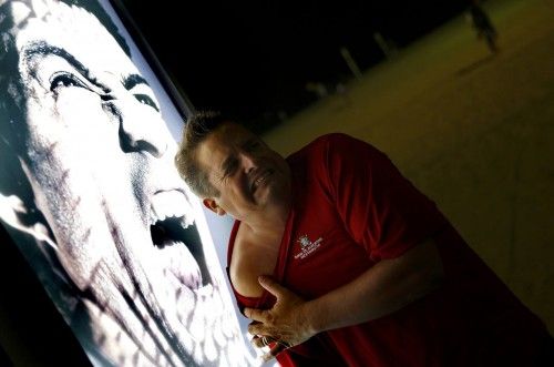 A man makes a funny face as he poses for a photograph next to an advertising placard showing Uruguay's striker Luis Suarez flashing his teeth at Copacabana beach in Rio de Janeiro