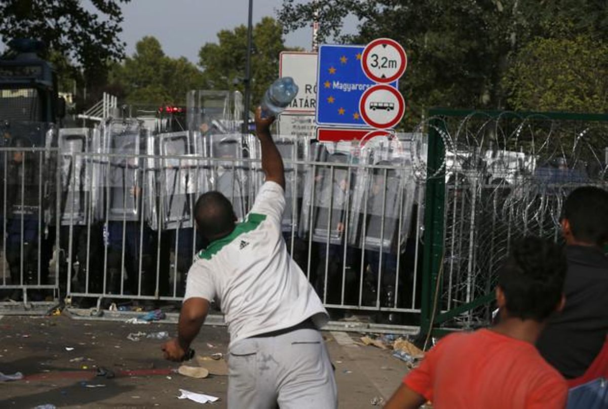 Un refugiat serbi llança objectes contra la policia hongaresa a la frontera amb Sèrbia.