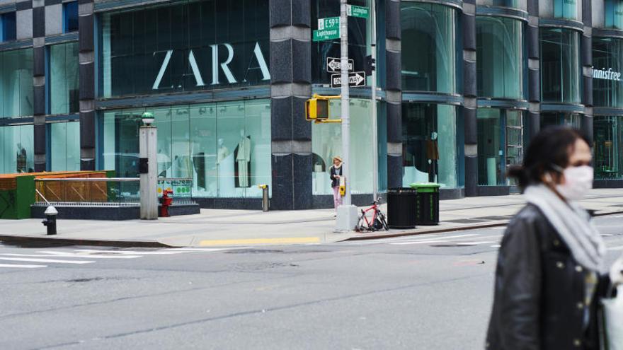 Una mujer con una mascarilla camina delante de una tienda de Zara.