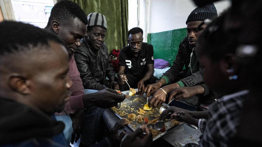 Inmigrantes africanos comparten un arroz en una vivienda del Besòs, en Barcelona.