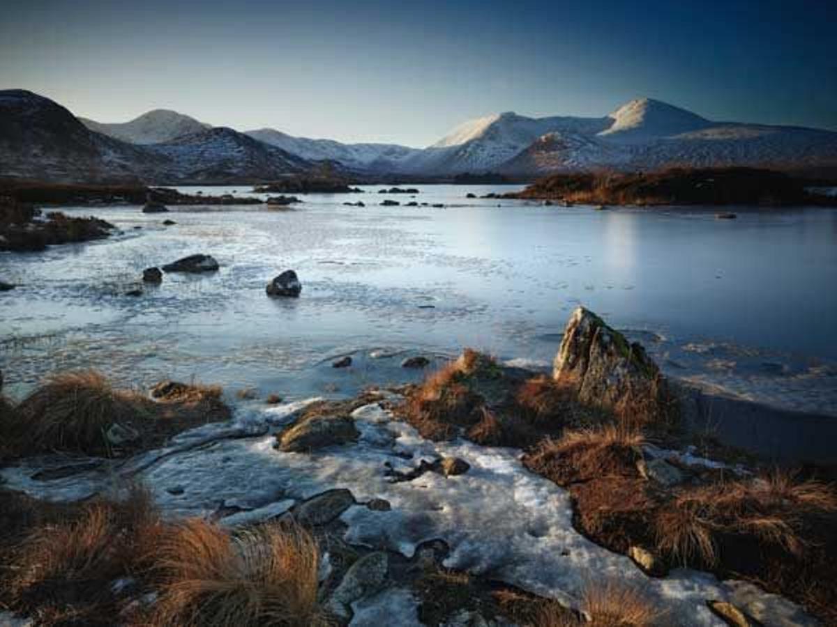 El sol trata de bañar las placas de hielo sobre un lago de las Highlands escocesas al amanecer.