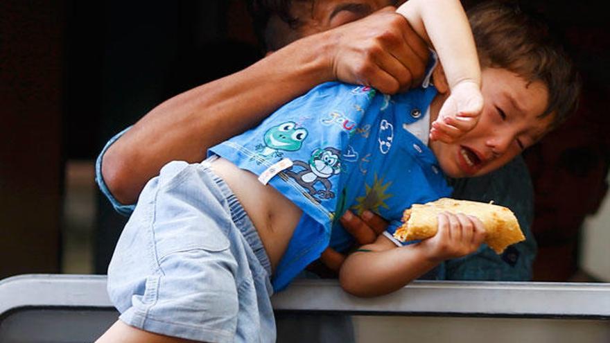 Un emigrante recoge a un niño desde la ventanilla de un tren en Hungría // EFE