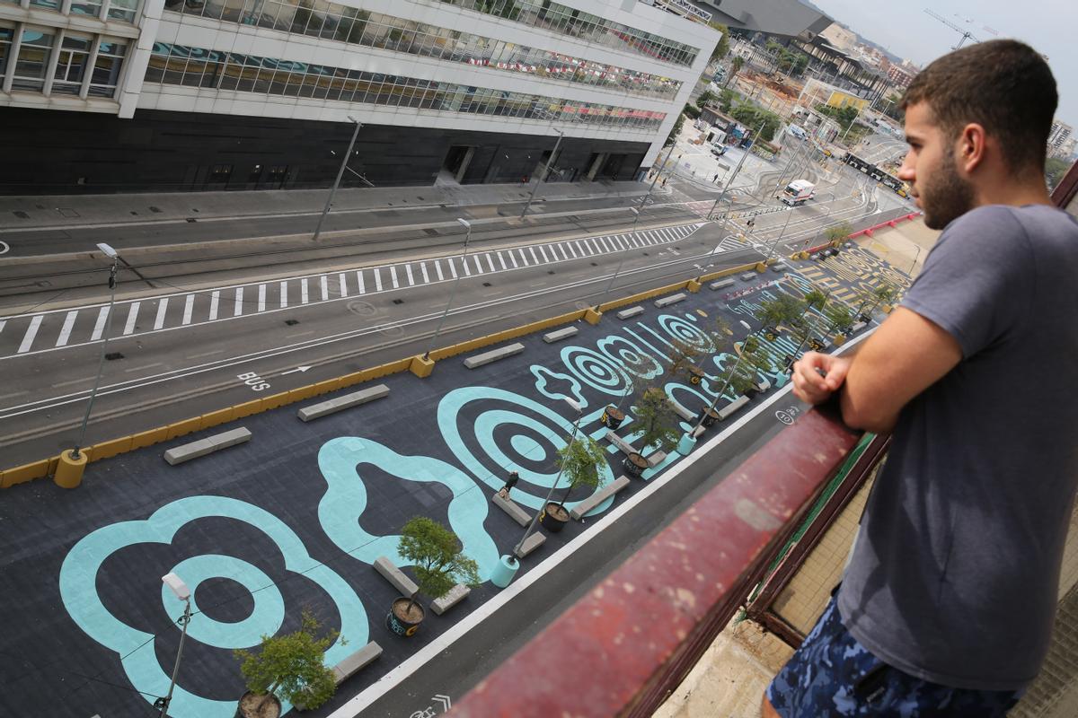 Un vecino contempla la nueva alfombra de urbanismo táctico de la Gran Via, desde el balcón de su casa