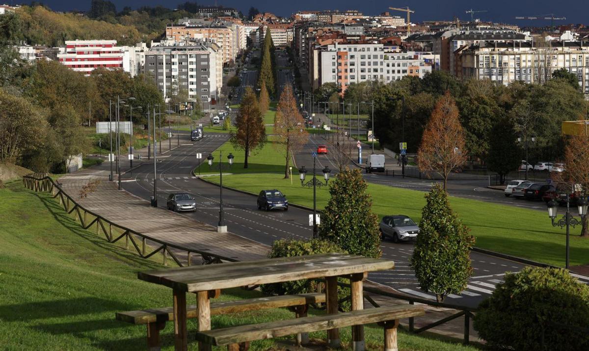 Edificios en el entorno de la rotonda de Las Campas. Sobre estas líneas, tres jóvenes cruzan el paso de peatones junto a la glorieta.