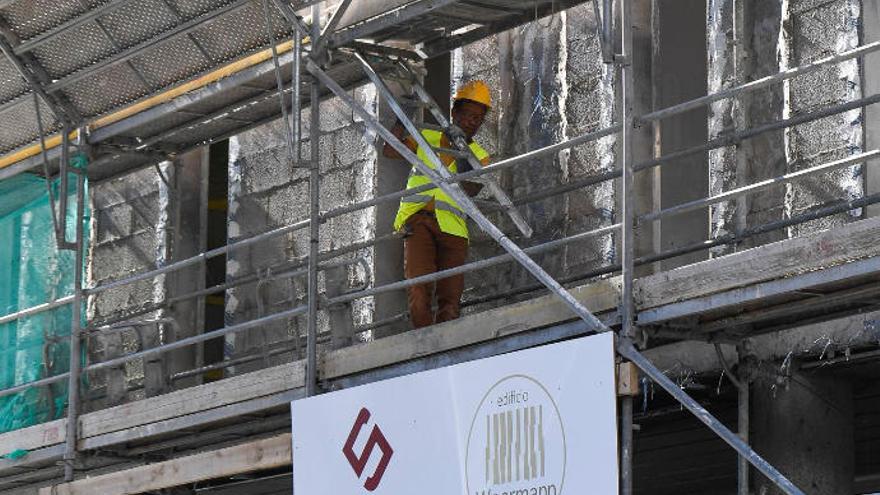 Un trabajador de la construcción desarrolla su labor en un andamio.