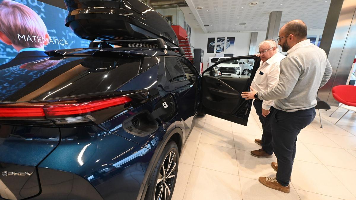 Una persona conoce las características de un vehículo electrificado en un concesionario de coches de Castellón.