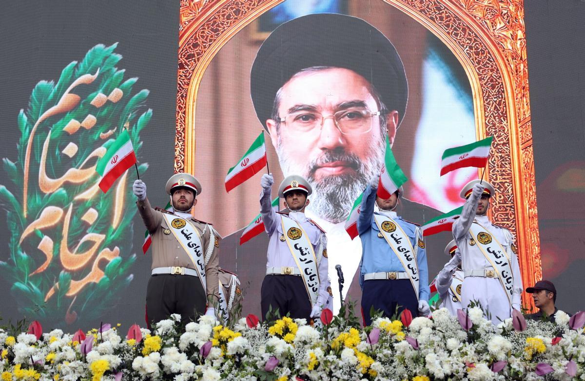 Miembros del Ejército iraní ondean banderas nacionales frente a un cartel del líder supremo iraní, el ayatolá Mojtaba Khamenei, durante una manifestación en Teherán, el 29 de abril de 2026.