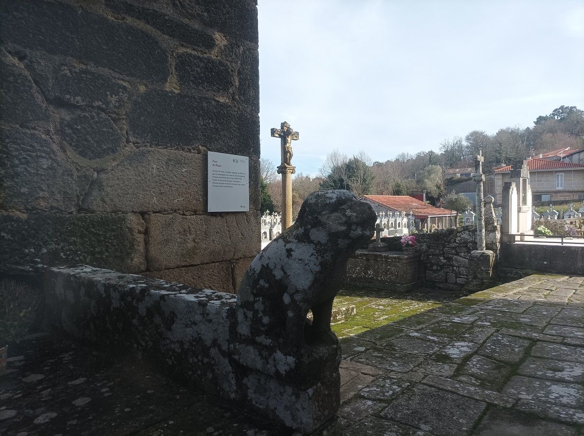 Escultura en la entrada de la casa rectoral, con el cementerio al fondo