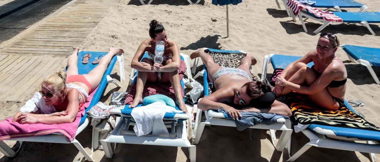 Turistas británicos tomando el sol en la zona de hamacas de la playa de Levante de Benidorm.