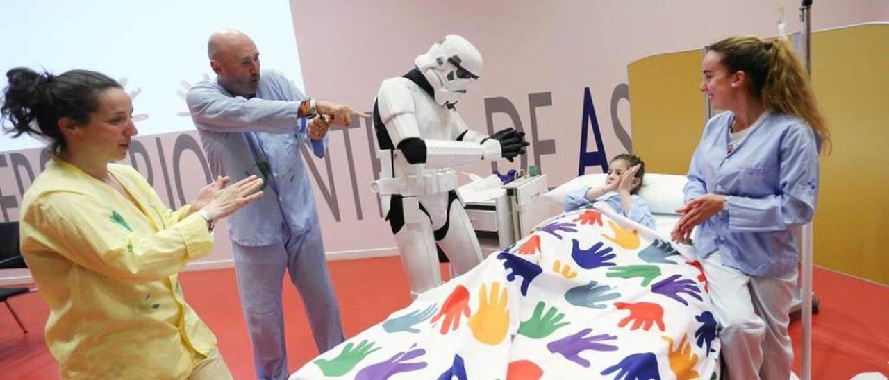 Uno de los soldados imperiales de Star Wars y varios voluntarios, durante la actuación de ayer con niños en el salón de actos del HUCA.