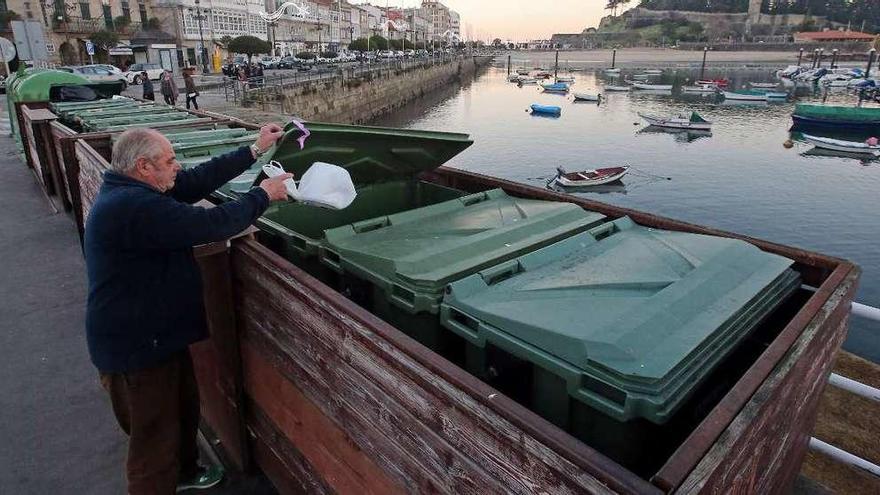 Un vecino deposita basura en los contenedores del muelle. // Marta G. Brea