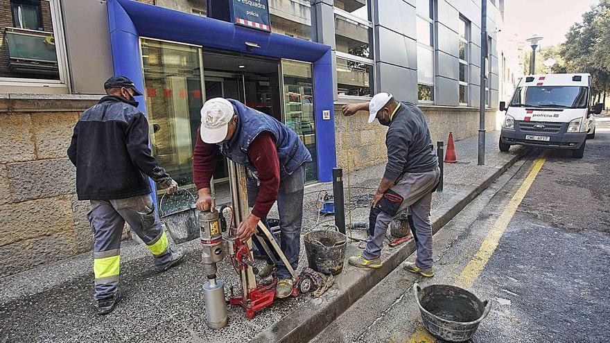 Operaris instal·lant les pilones de seguretat a la comissaria dels Mossos a Girona.