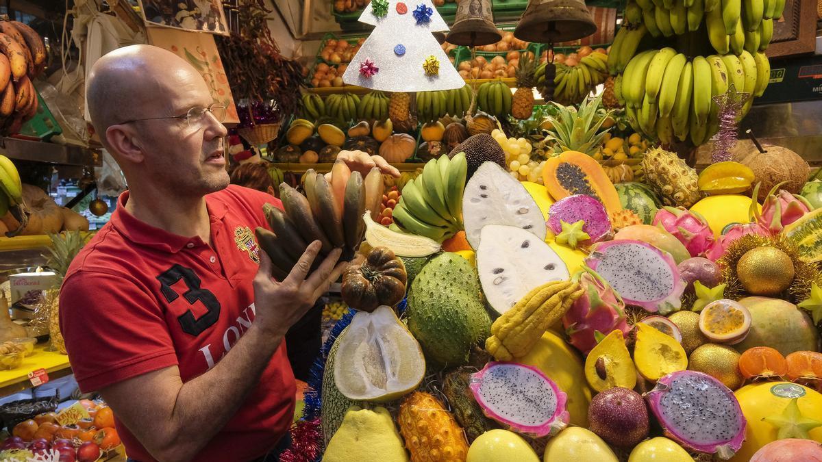 El frutero José Quintana coloca una manojo de plátanos rojos en su puesto del Mercado de Vegueta, en Gran Canaria.