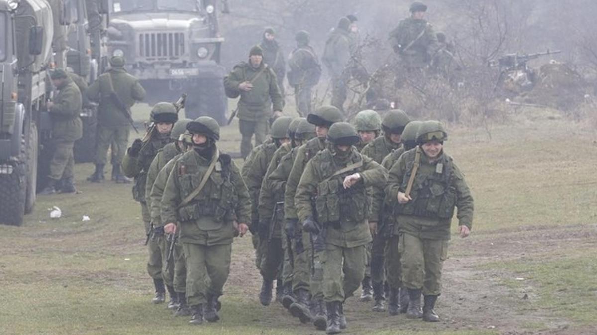 Un grupo de soldados armados, presuntamente rusos, caminan cerca de un acceso a la base de Perevalnoye, en los alrededores de Simferópol (Crimea), este viernes.