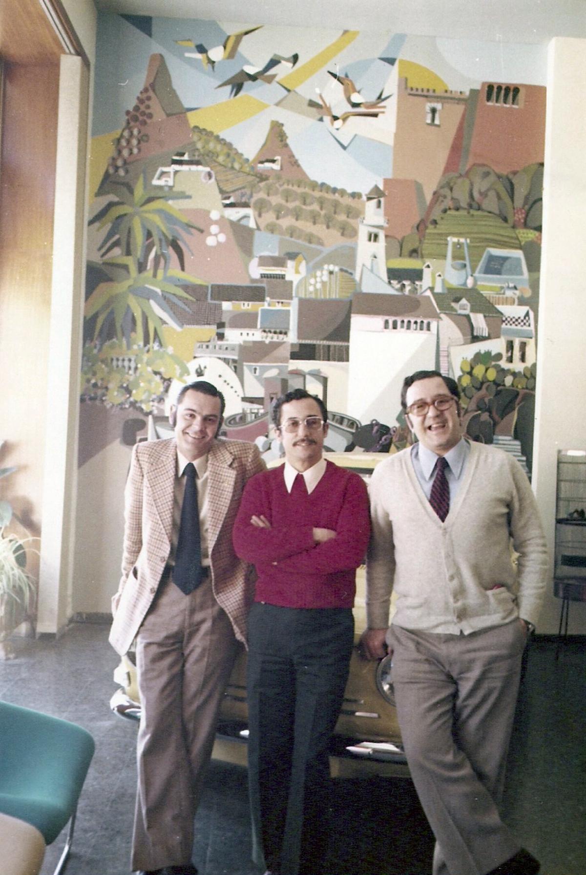 Gonzalo Rojo (izq.), Jaime Rodríguez Barroso y Julián Sesmero, en 1974, delante del mural artístico de Paco Moreno Ortega que presidía el hall de la emisora en la Alameda de Colón.