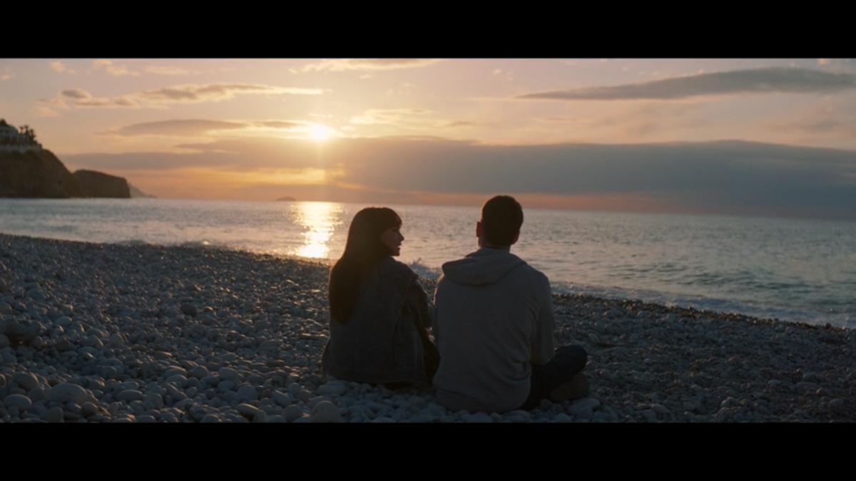 La pareja protagonista, en la playa de La Caleta viendo el anochecer del litoral vilero