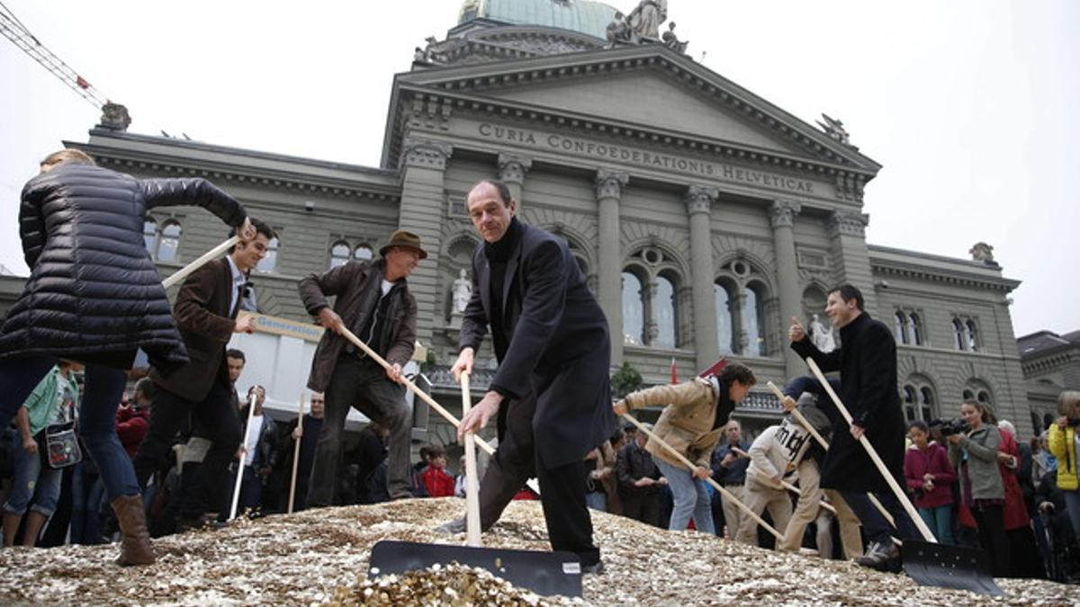 Activistas colocan céntimos en el suelo a las puertas del Parlamento en Berna, el pasado día 4.