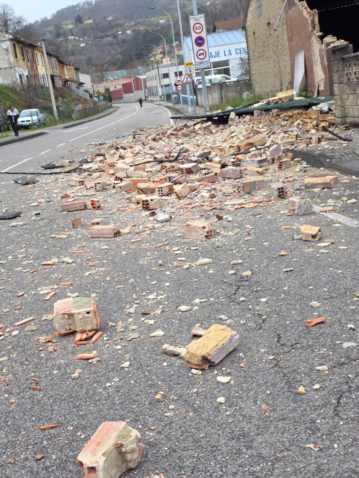 El muro, derrumbado sobre la carretera de entrada a El Entrego.