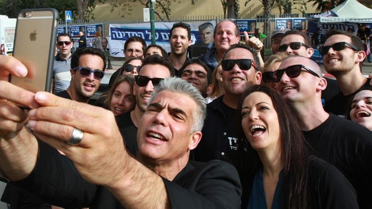 Yair Lapid, líder del partido de centroderecha Yesh Atid, se hace un selfi con su mujer y varios seguidores, tras votar este martes.