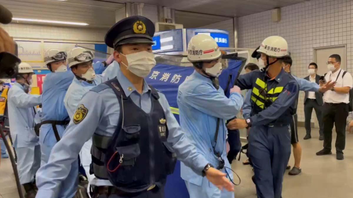 Agentes de policía escoltan a miembros de los equipos de rescate que llevan a una persona herida en un ataque con un cuchillo en un tren de Tokyo.