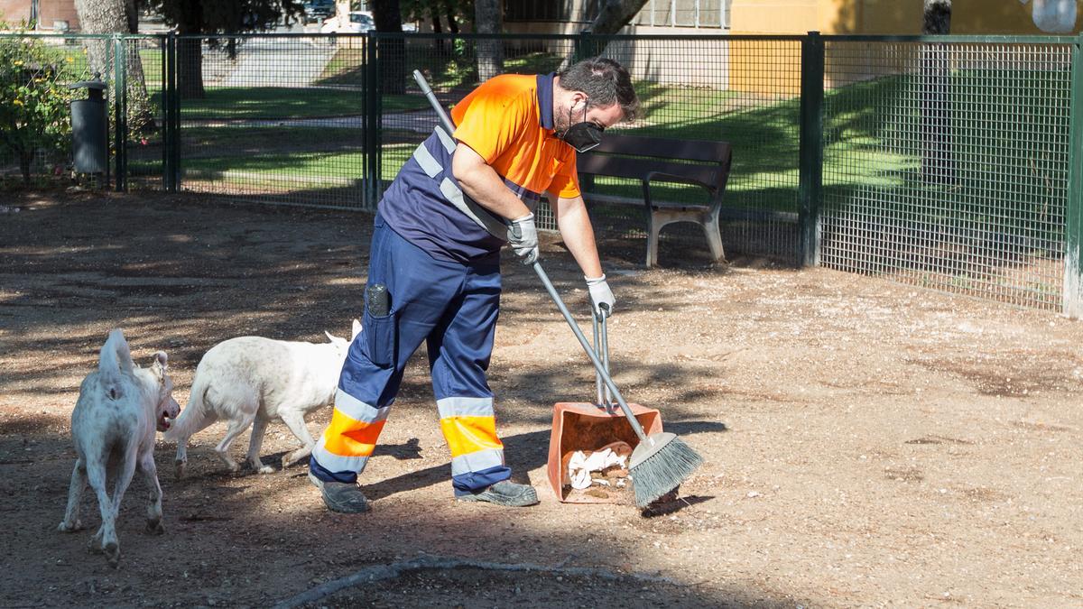 Un operario se encarga de la limpieza de un parque canino.