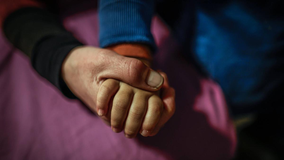 Una madre toma la mano de su hijo.