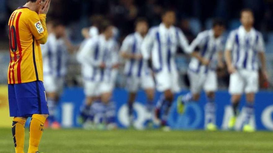 Messi se echa las manos a la cara mientras los jugadores de la Real Sociedad festejan el gol. // Efe