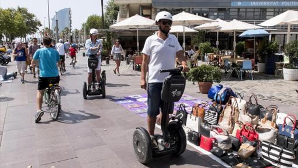 Bicicletas, segways, top manta y peatones en el paseo de Joan de Borbó, el martes pasado.