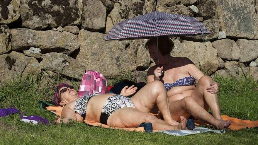 Dos mujeres, al sol ayer en la zona termal del Muiño da Veiga, a la orilla del Miño. // Brais Lorenzo