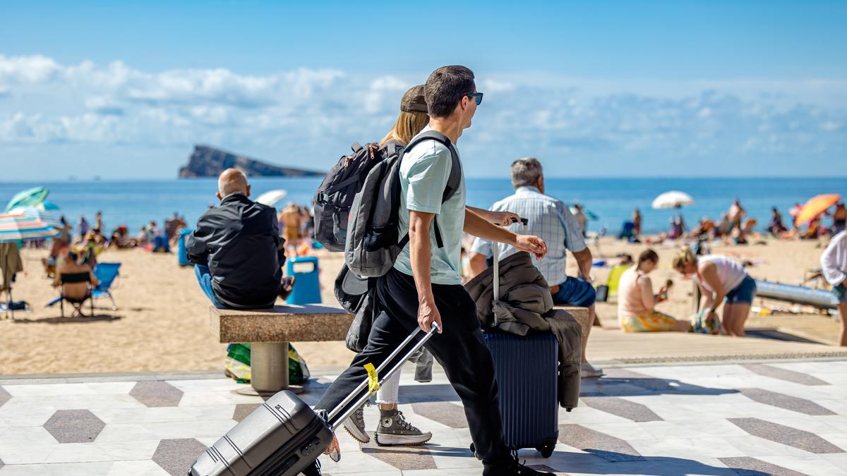 Turistas cargando con las maletas en primera línea de playa en Benidorm.