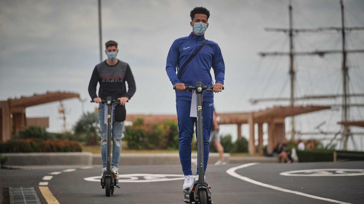 Dos jóvenes circula por Santa Cruz en patinete.