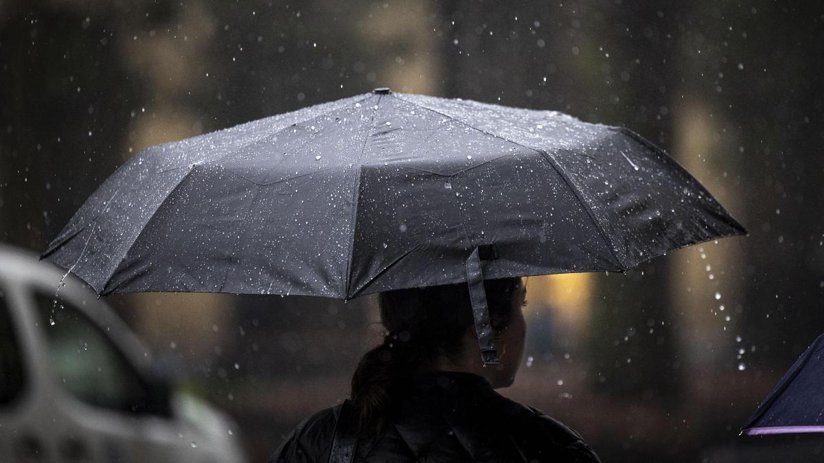 Una mujer camina bajo la lluvia con su paraguas por una calle de San Sebastián