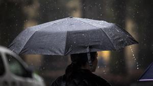 Una mujer camina bajo la lluvia con su paraguas por una calle de San Sebastián