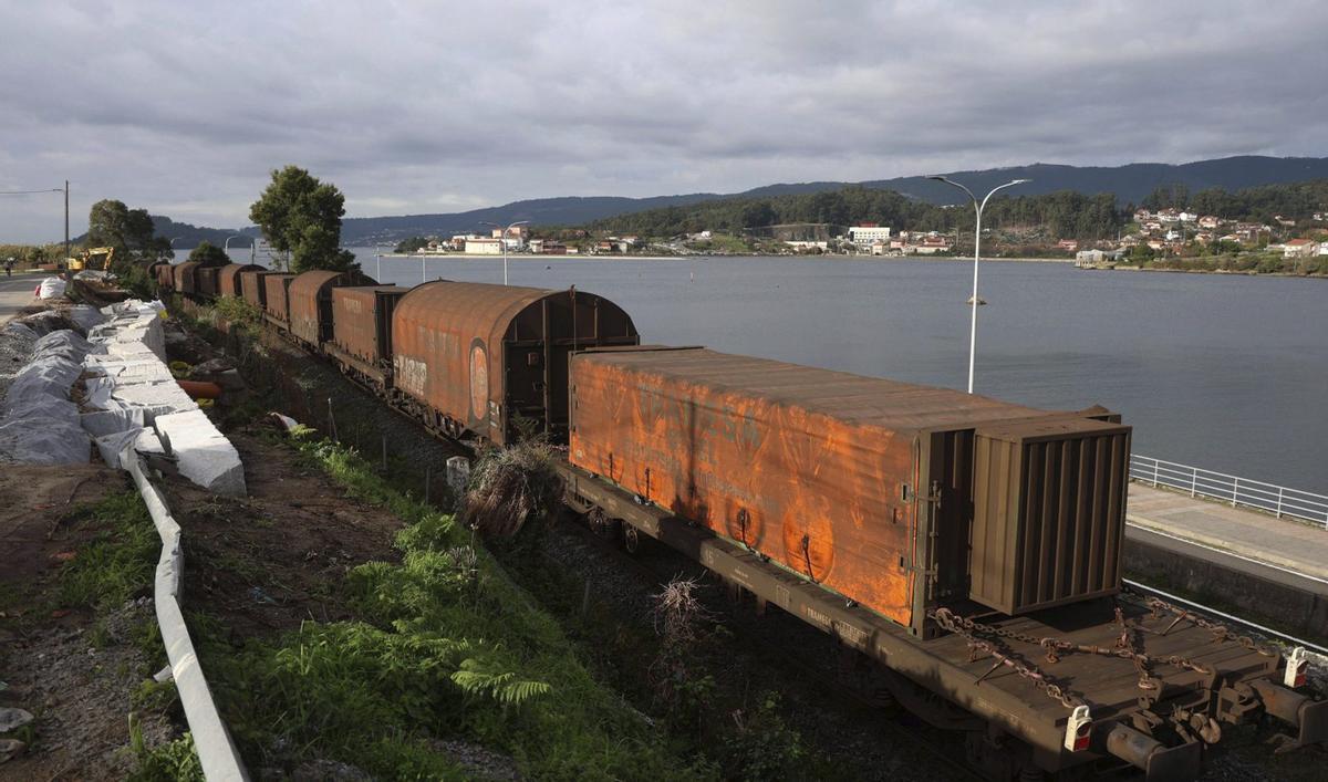 Un tren circula por el ramal ferroviario al Puerto por la zona de Mollavao, a orillas de la ría.