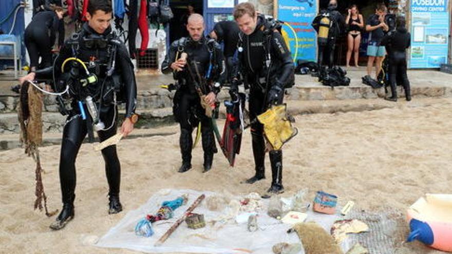 Tres submarinistes deixant les deixalles que han recollit al fons del mar