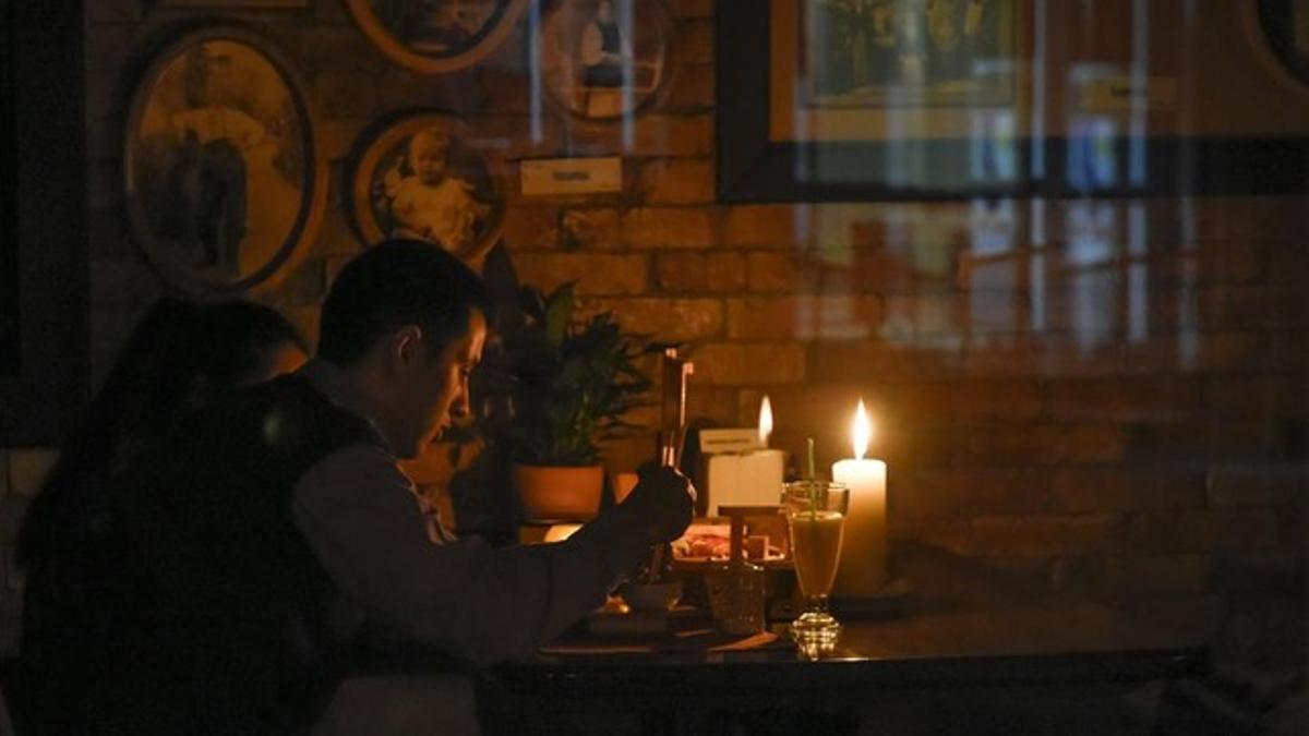 Un hombre cena en un restaurante a la luz de las velas tras el apagón general producido este domingo.