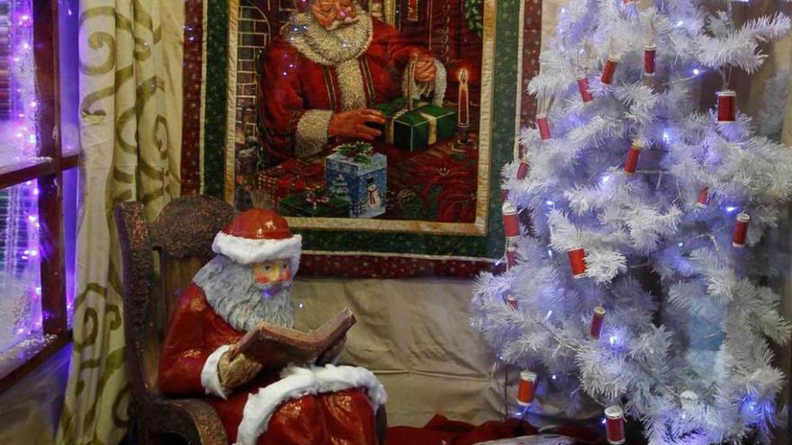 premio con belén, máquinas de coser ramón rodríguez. Una muestra con Papá Noel leyendo un libro y un árbol blanco como elementos destacados.
