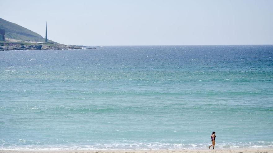 Una bañista pasea por la playa de Riazor.