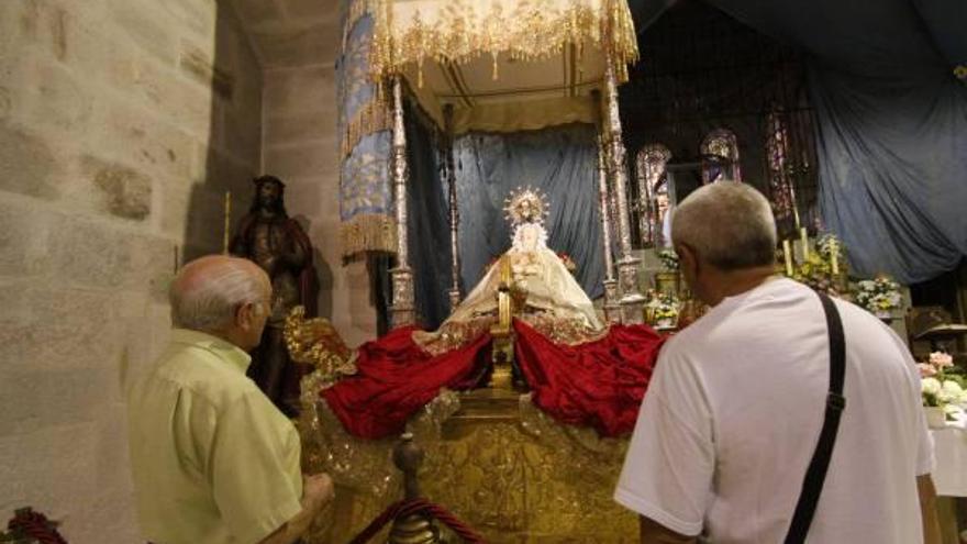 Varios hombres observan la imagen en el trono en el interior de la iglesia conventual.