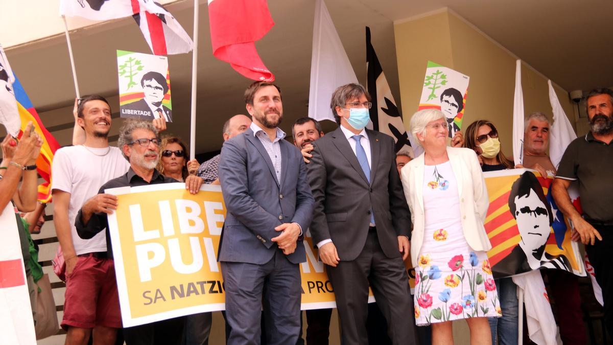 Puigdemont, Comín i Ponsatí a la sortida del tribunal de Sàsser i davant una pancarta de suport, el 4 d&#039;octubre del 2021 (horitzontal)