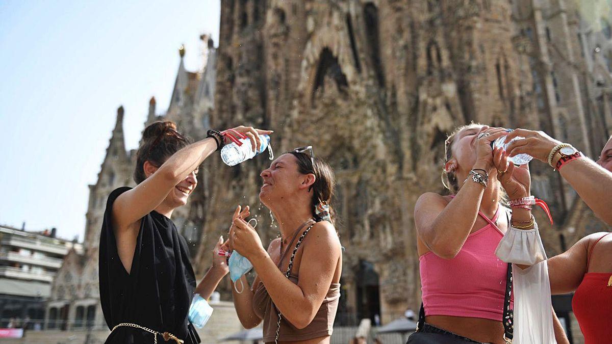 Turistes refrescant-se ahir davant la Sagrada Família de Barcelona.