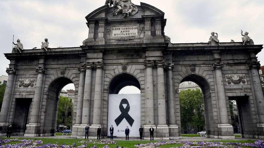 Representantes políticos de Madrid ante la Puerta de Alcalá, con un crespón negro.