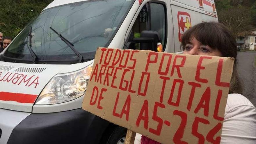 Marta Vena, con una de las pancartas que urgen el arreglo de la carretera AS-254 que une Piloña y Caso.